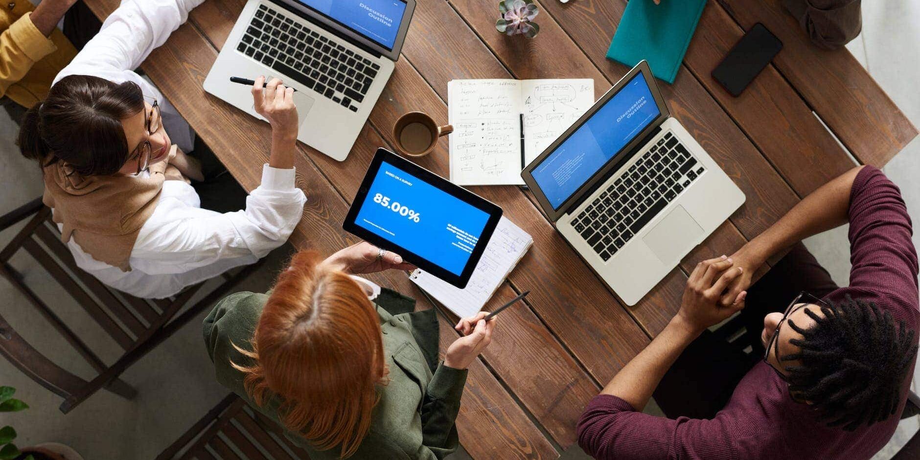 top view photo of group of people using macbook while discussing