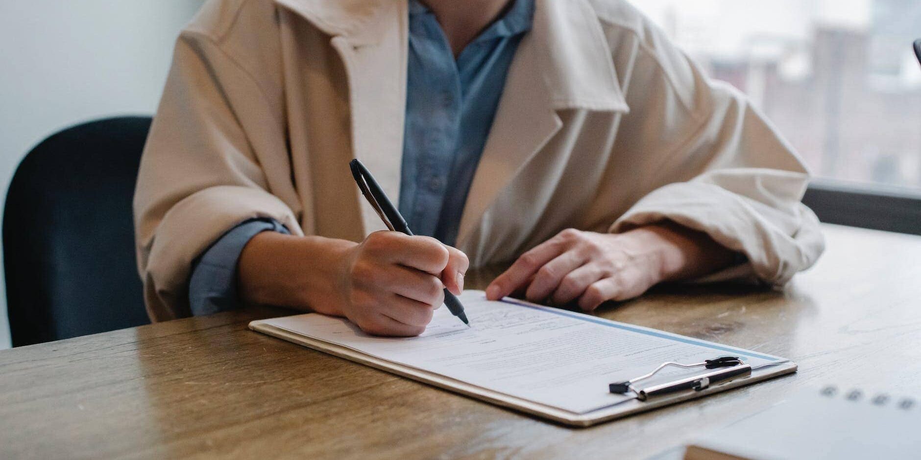 focused woman writing in clipboard while hiring candidate