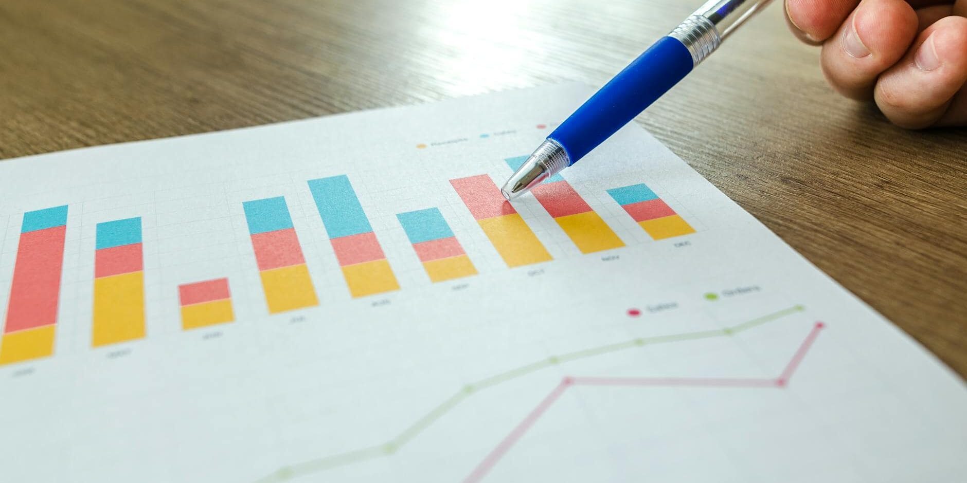 person holding pen pointing at graph