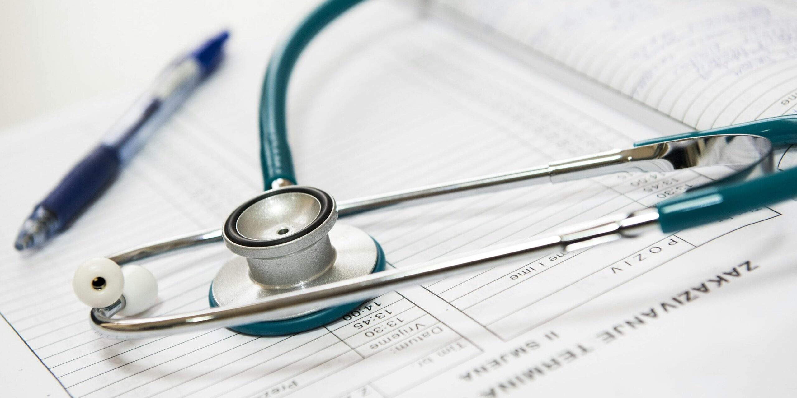 Image of a stethoscope and a pen on a notepad.